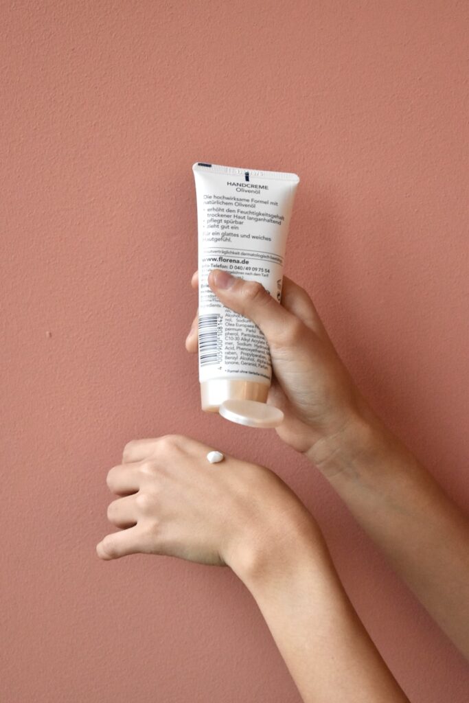 a hand holding a tube of cream