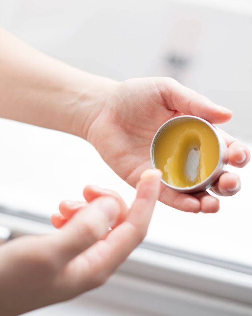 person holding yellow round ointment